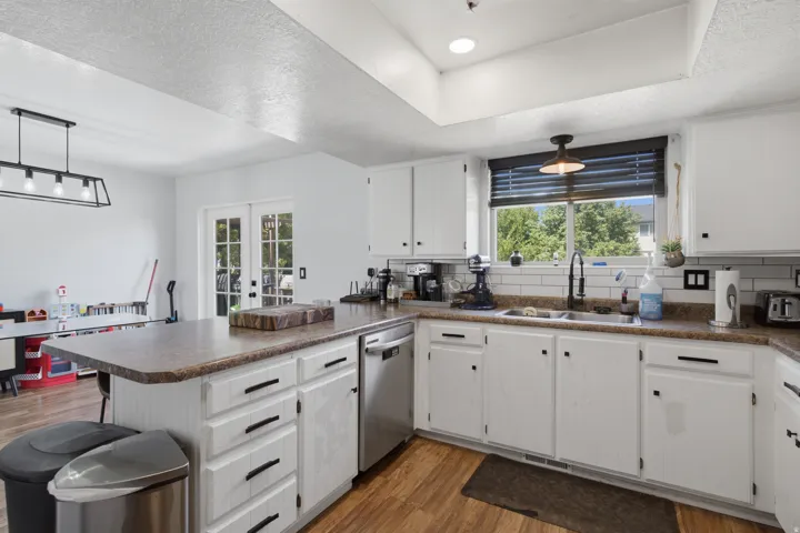 Kitchen featuring white cabinetry, wood-finish flooring, a stainless steel dishwasher