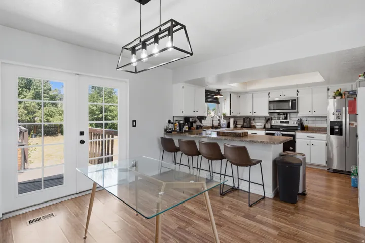 Kitchen featuring white cabinetry, subway tile backsplash, stainless steel appliances, and a breakfast bar