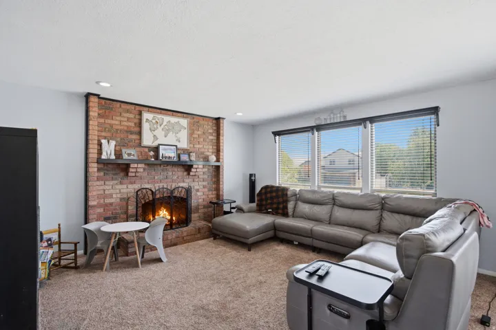 Brick fireplace with a substantial hearth, three large windows, and recessed lighting