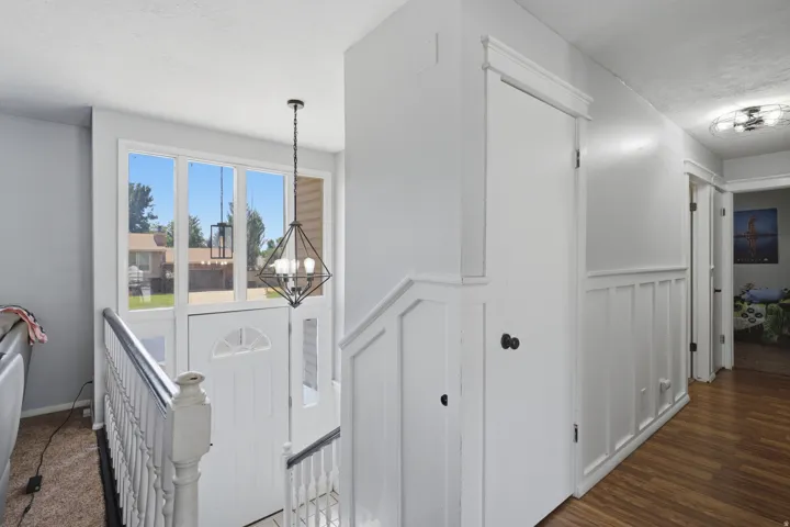 Entryway featuring a decorative transom window, an overhead geometric light fixture, and white wainscoting