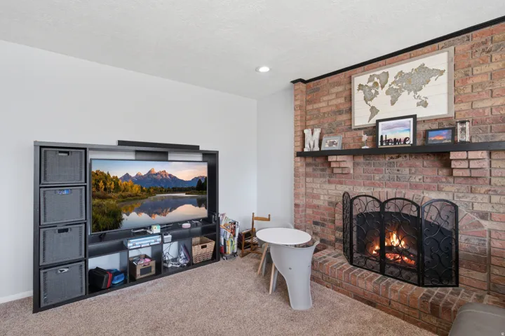 Brick-faced fireplace with a black mantel and an integrated fire screen