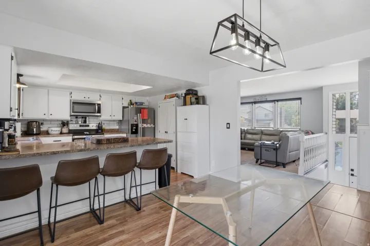 Kitchen with white shaker-style cabinetry, stainless steel appliances, and a breakfast bar with a stone-finish countertop