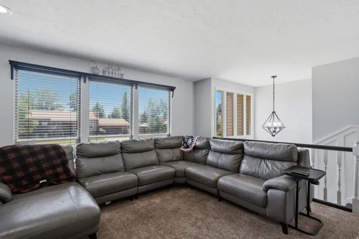 Triple window feature with blinds, textured ceiling, geometric pendant light fixture, and white painted railing