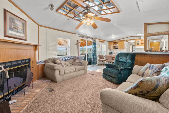 Living area featuring a wood-surround fireplace with a brick hearth, a ceiling fan, and sliding glass doors