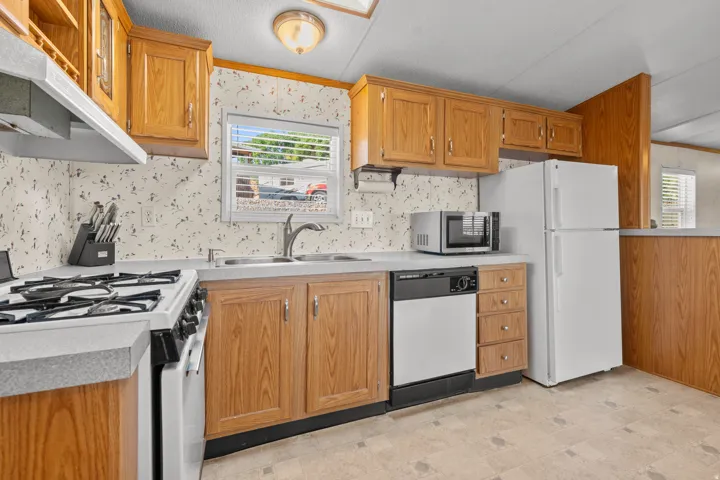 Kitchen featuring wood-finish cabinetry, a double basin sink, and a four-burner gas range