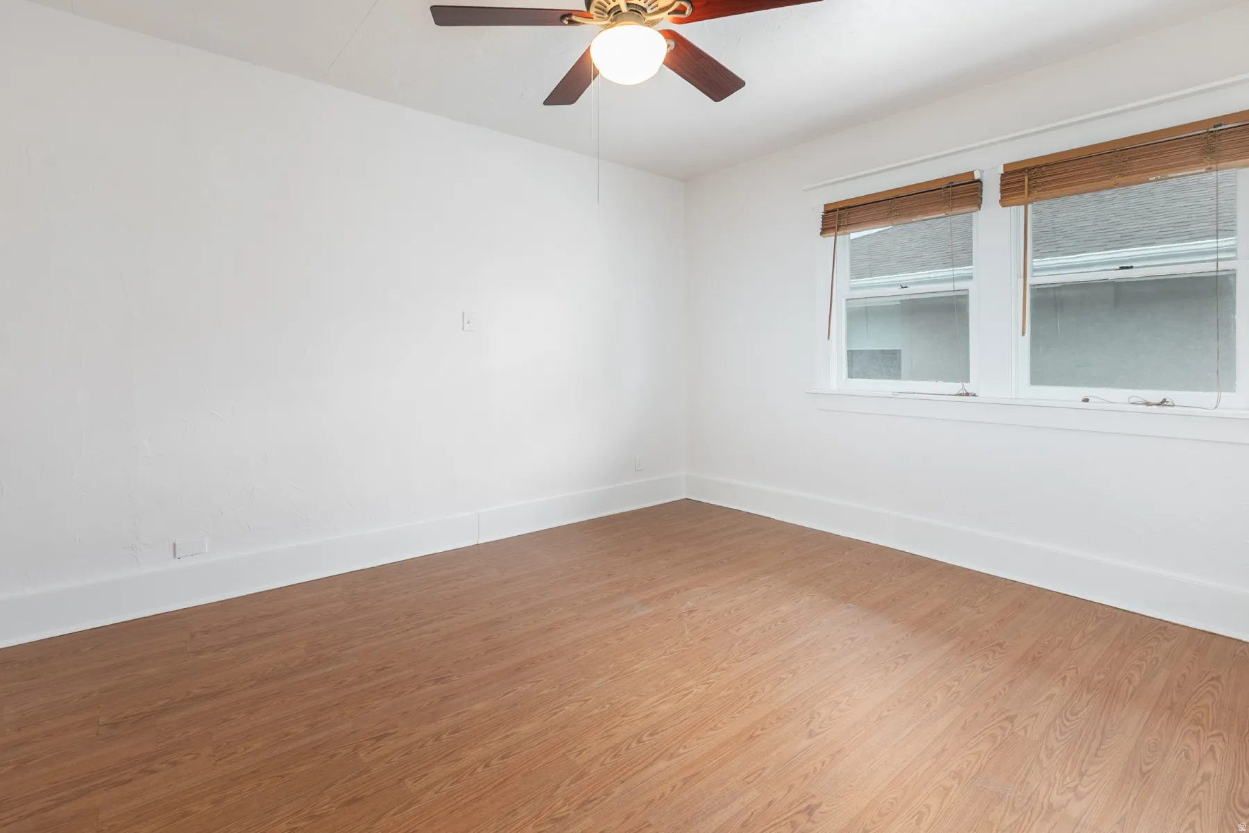 Wood-finish flooring, white walls, and a ceiling fan with integrated lighting