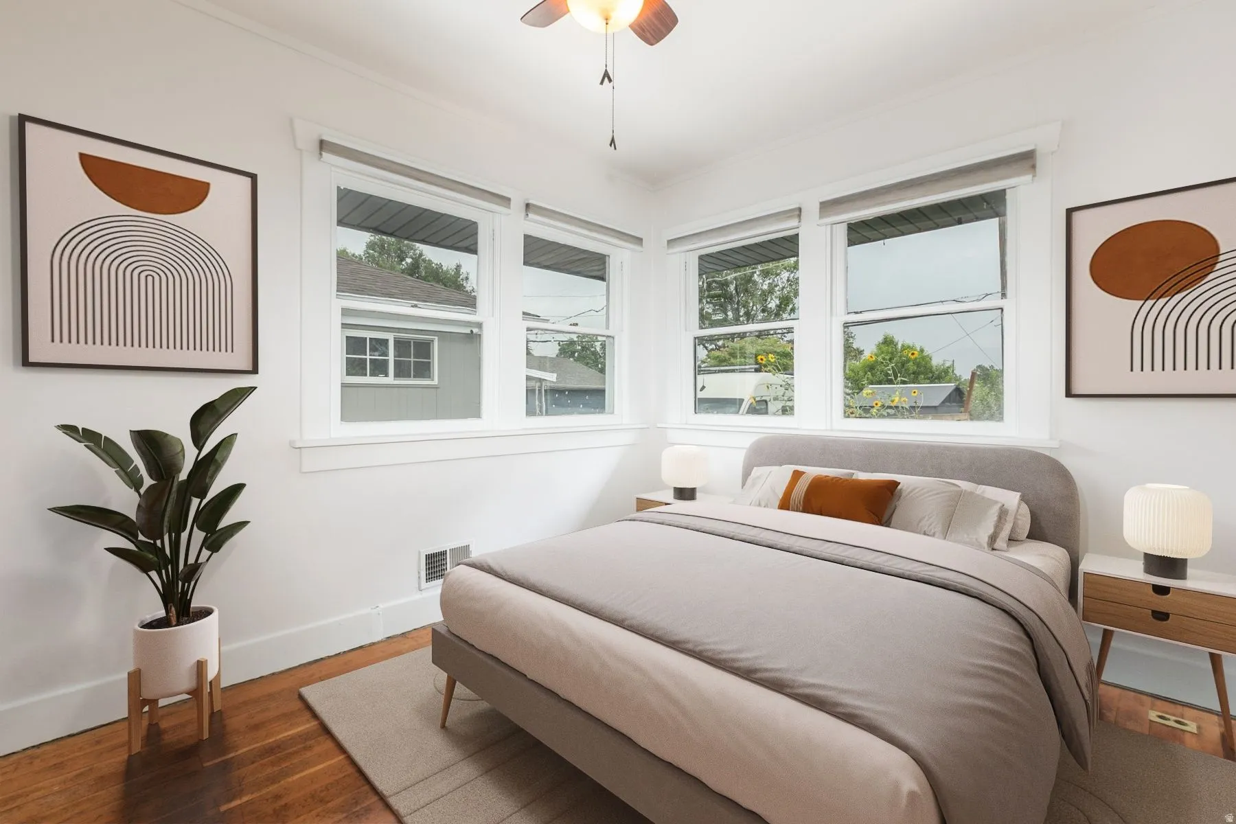 Hardwood flooring, corner windows, ceiling fan, white trim, and white walls