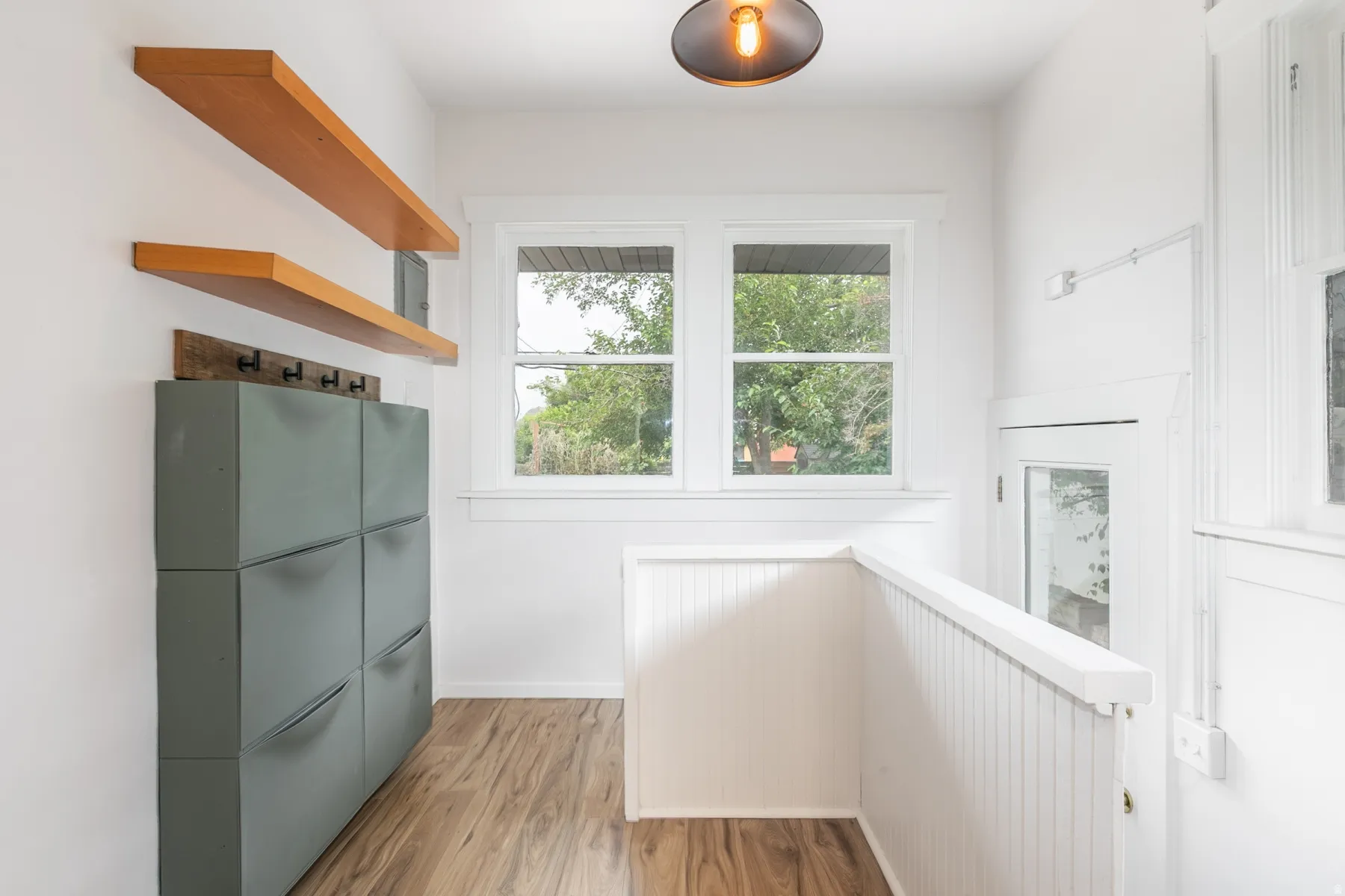 Bright interior with wood-finish flooring, white walls, and built-in wood shelving
