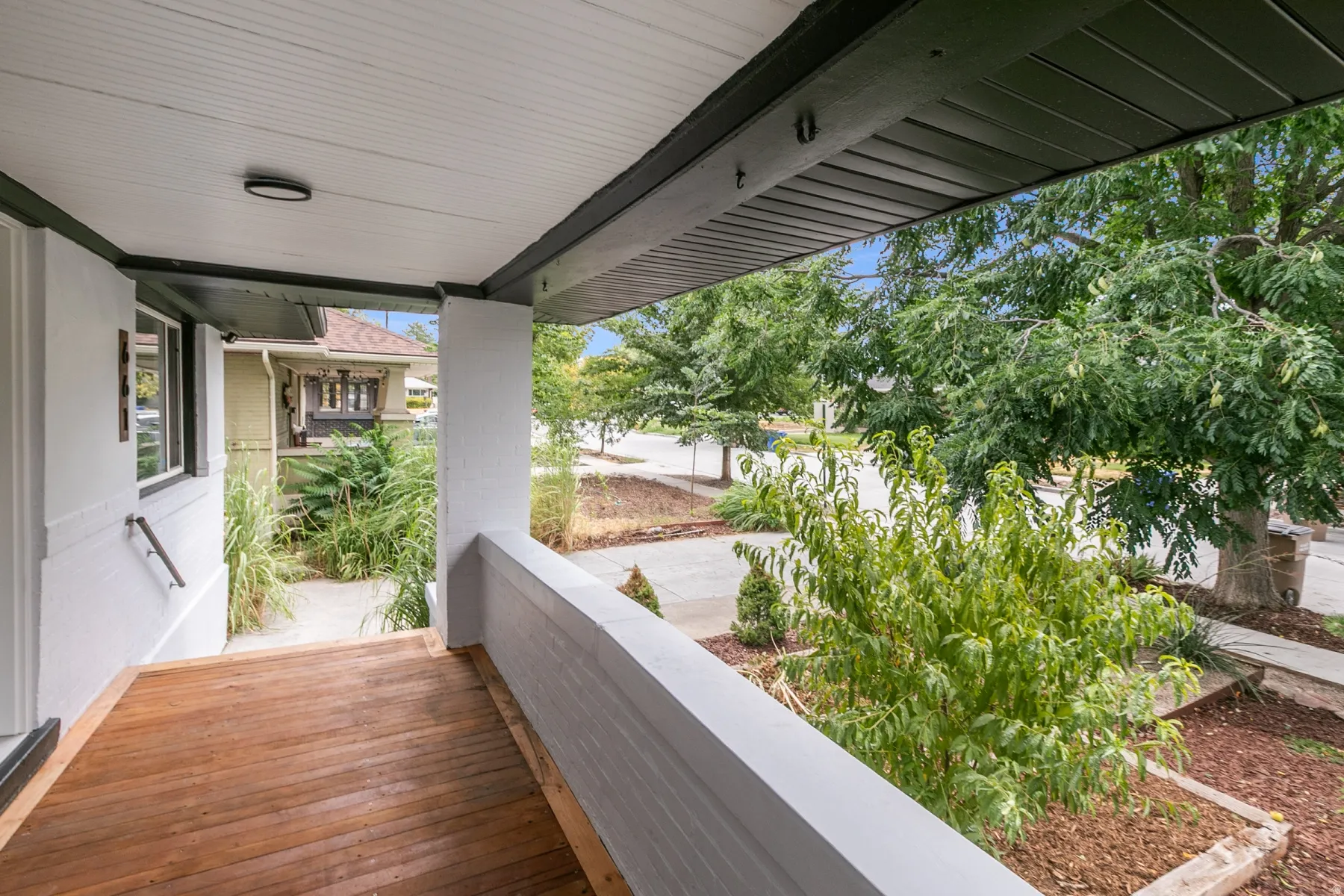 Covered porch with wood-finish decking, white brick railing, and overhead lighting