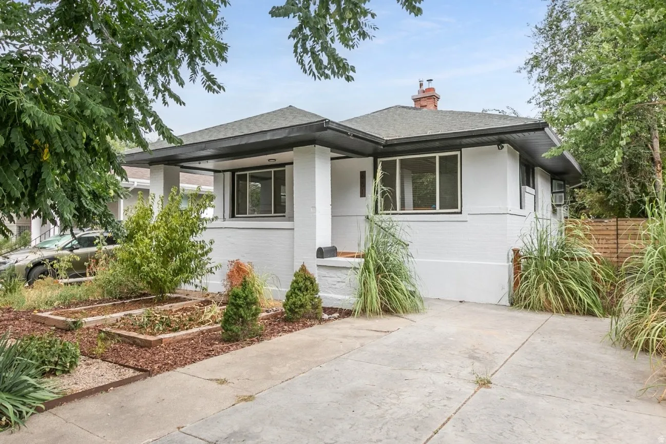 Single-level residence with a gray shingle roof, white brick exterior, and dark trim