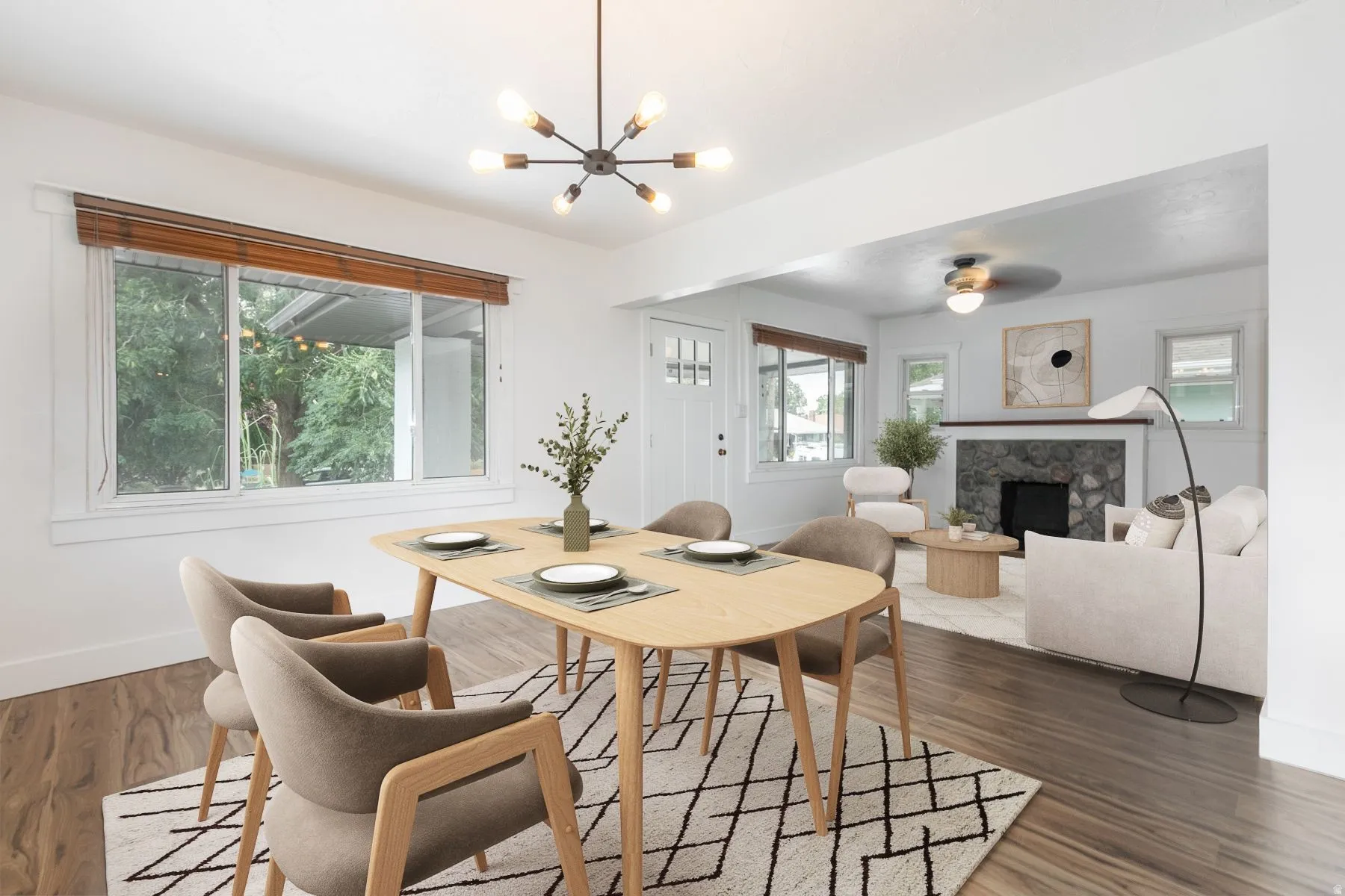 Open-concept interior featuring wood-finish flooring, a modern chandelier, and a stone-clad fireplace