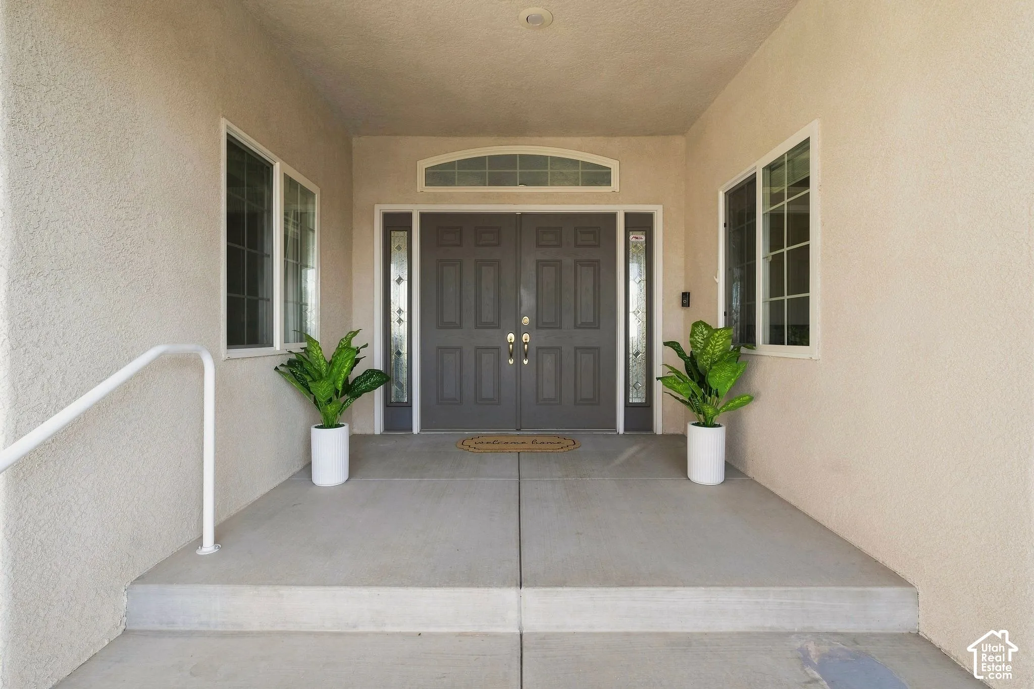 Double entry doors with decorative glass panels, transom window, and dual side windows