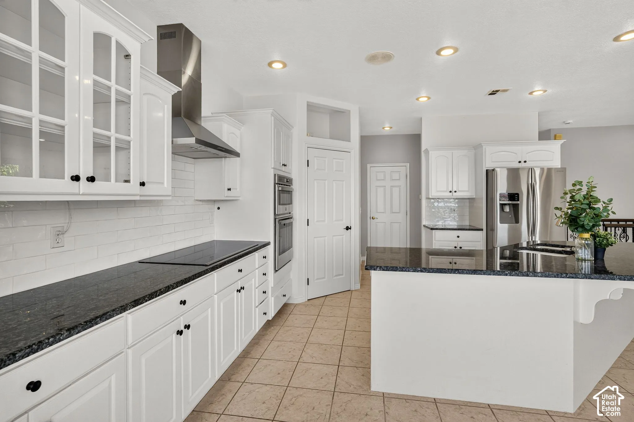 White cabinetry, dark countertops, tile flooring, stainless steel appliances, and recessed lighting