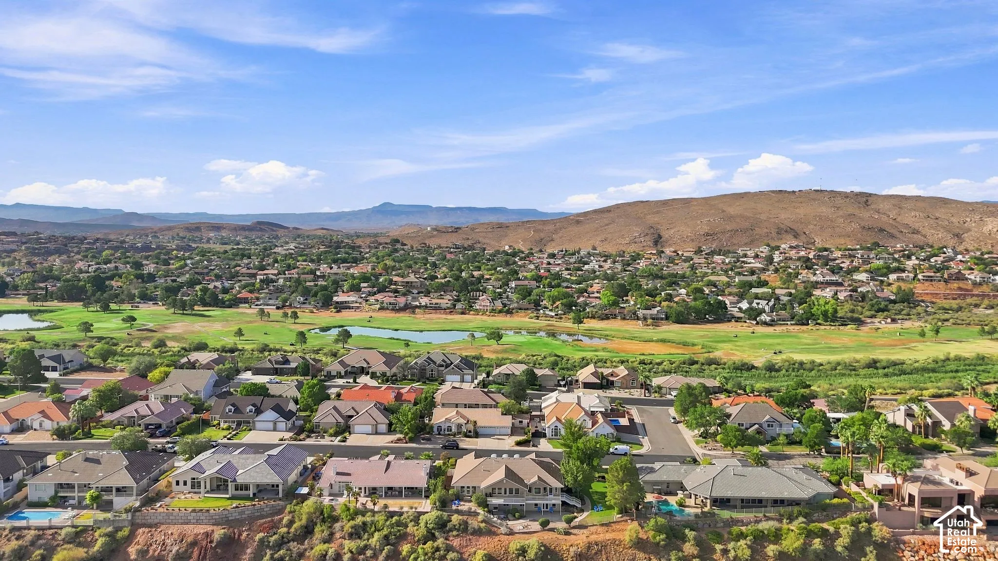 Aerial perspective showcasing a residential community with mature landscaping, a golf course, and natural terrain