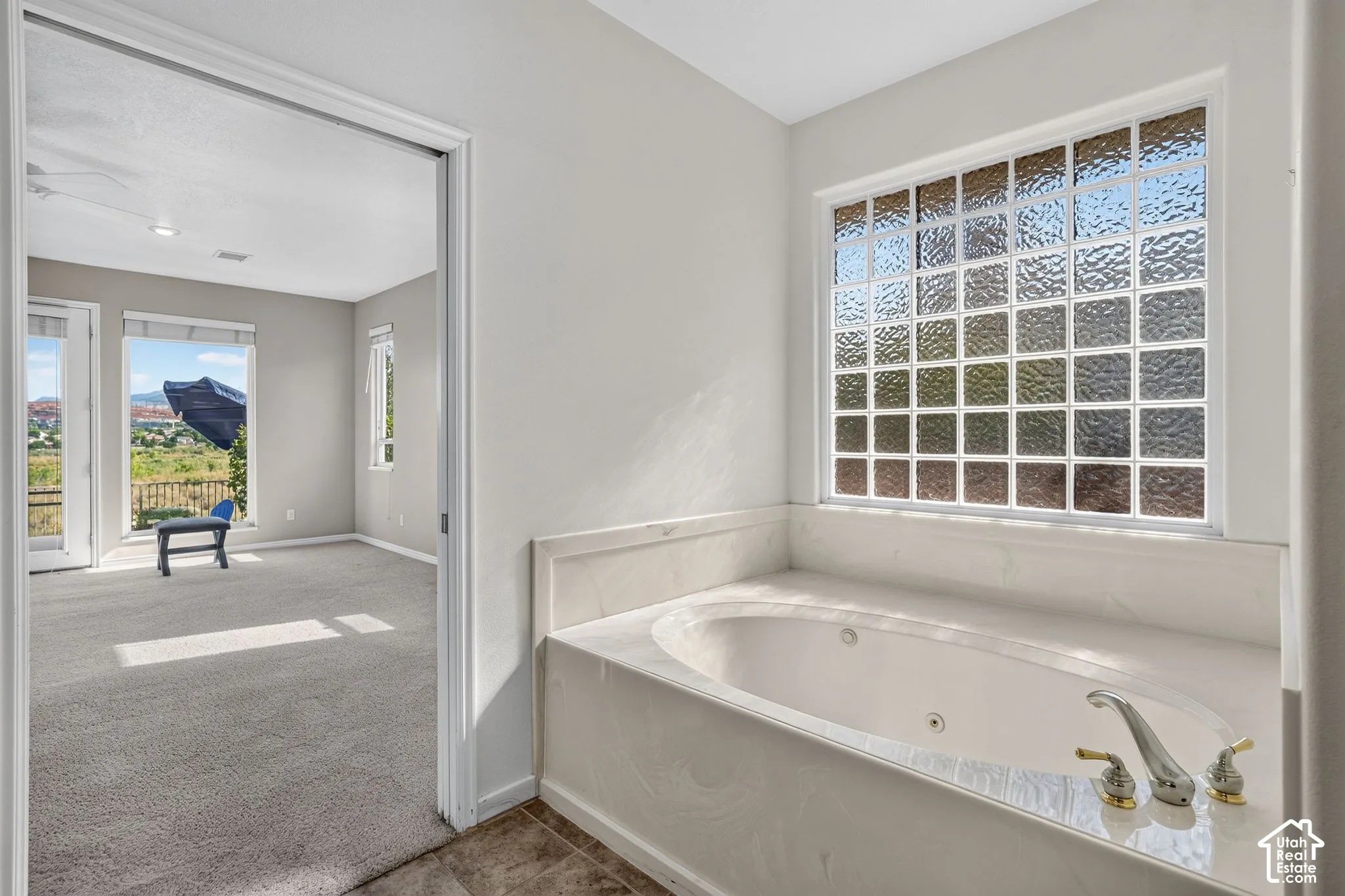 Jetted tub with a stone surround, glass block window, and dual-tone fixtures