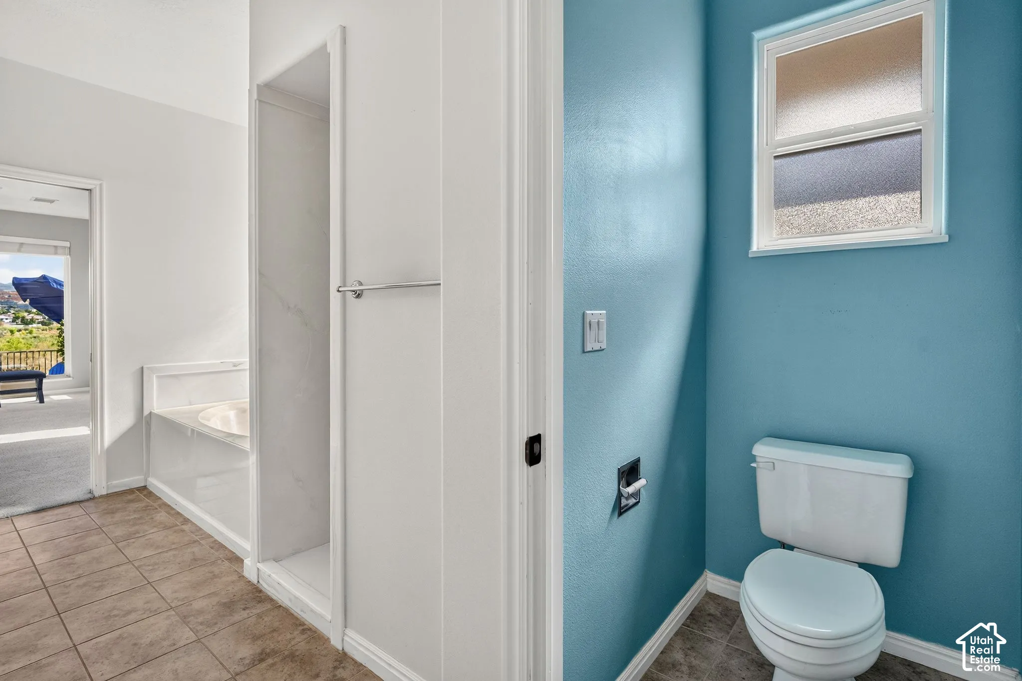 Spa-inspired bathroom featuring vibrant teal accent walls, a white ceramic toilet with elongated bowl, pedestal sink with chrome fixtures, and a frameless glass-enclosed shower enclosure with white subway tile surround