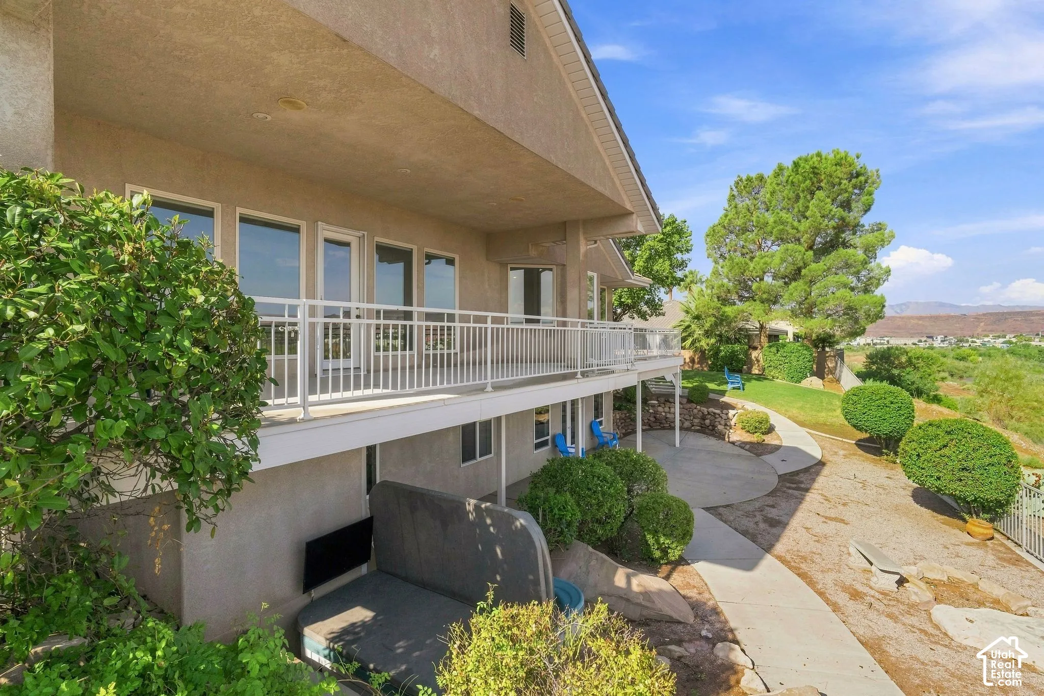 Multi-level residence with a stucco exterior, upper-level balcony, and ground-level patio