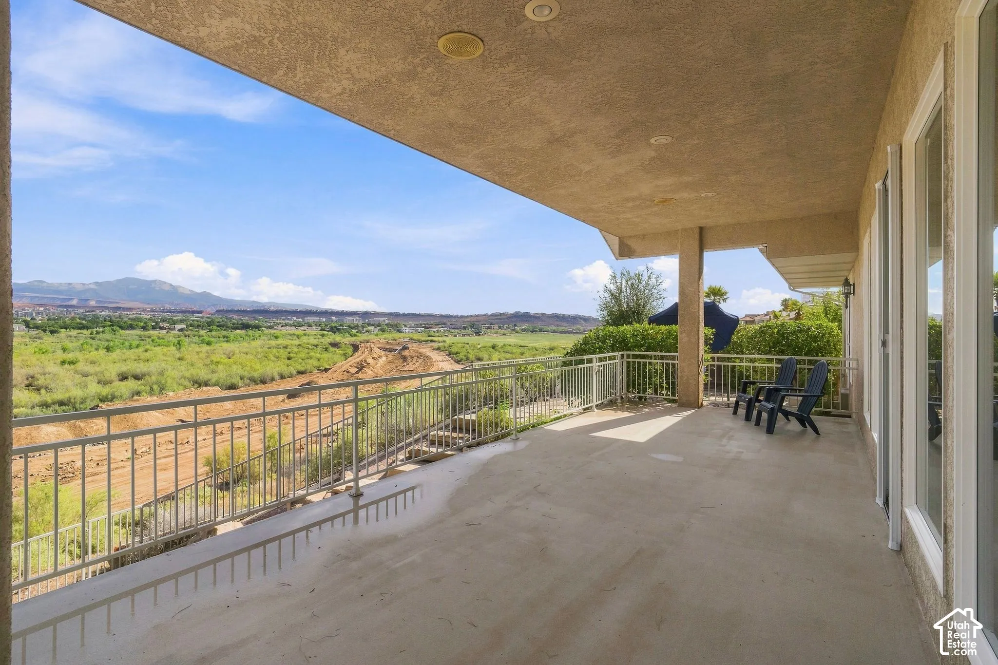 Expansive covered patio with concrete flooring, recessed lighting, and a metal railing