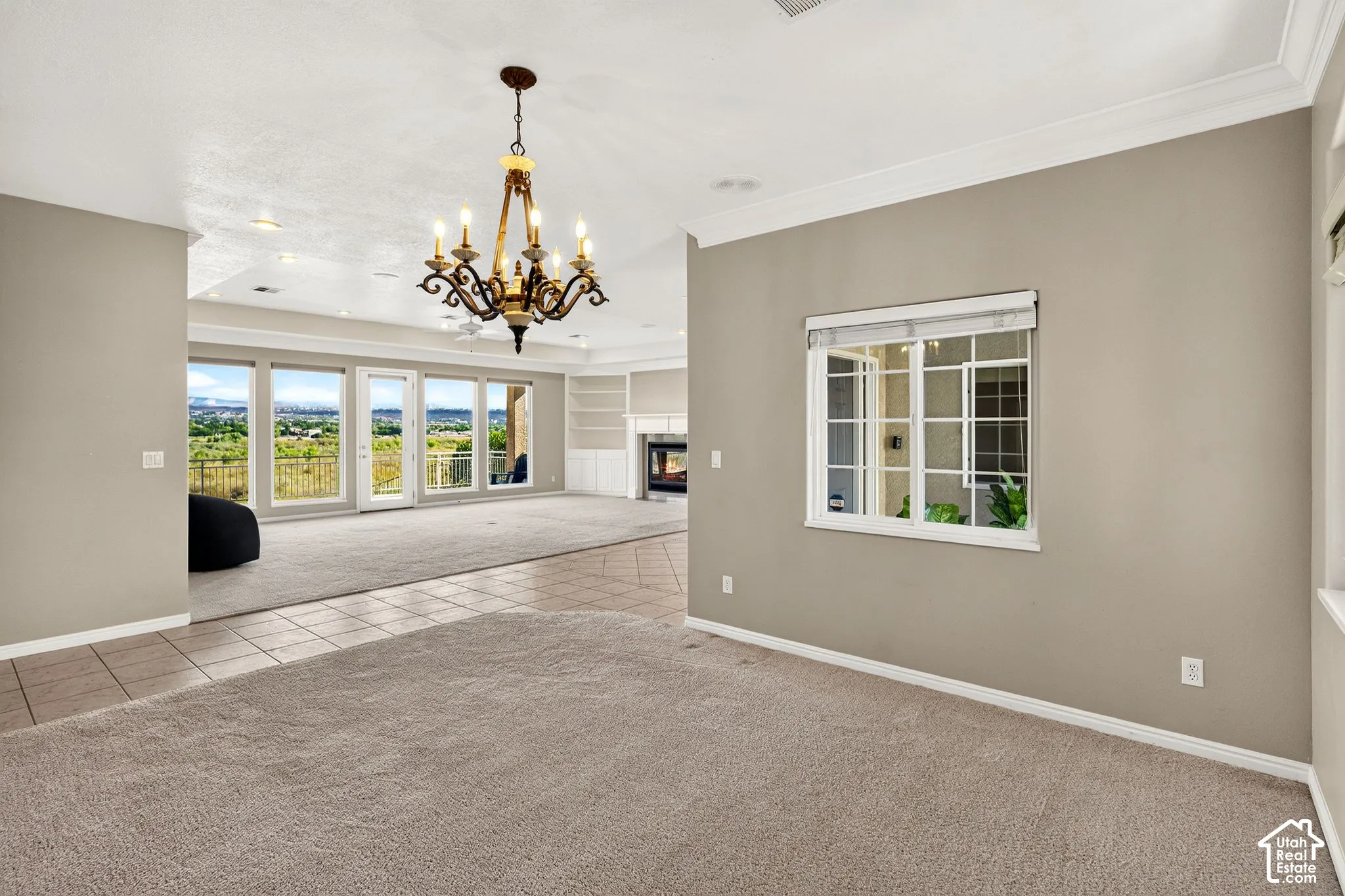 Expansive room featuring a decorative chandelier, large windows, and a built-in fireplace