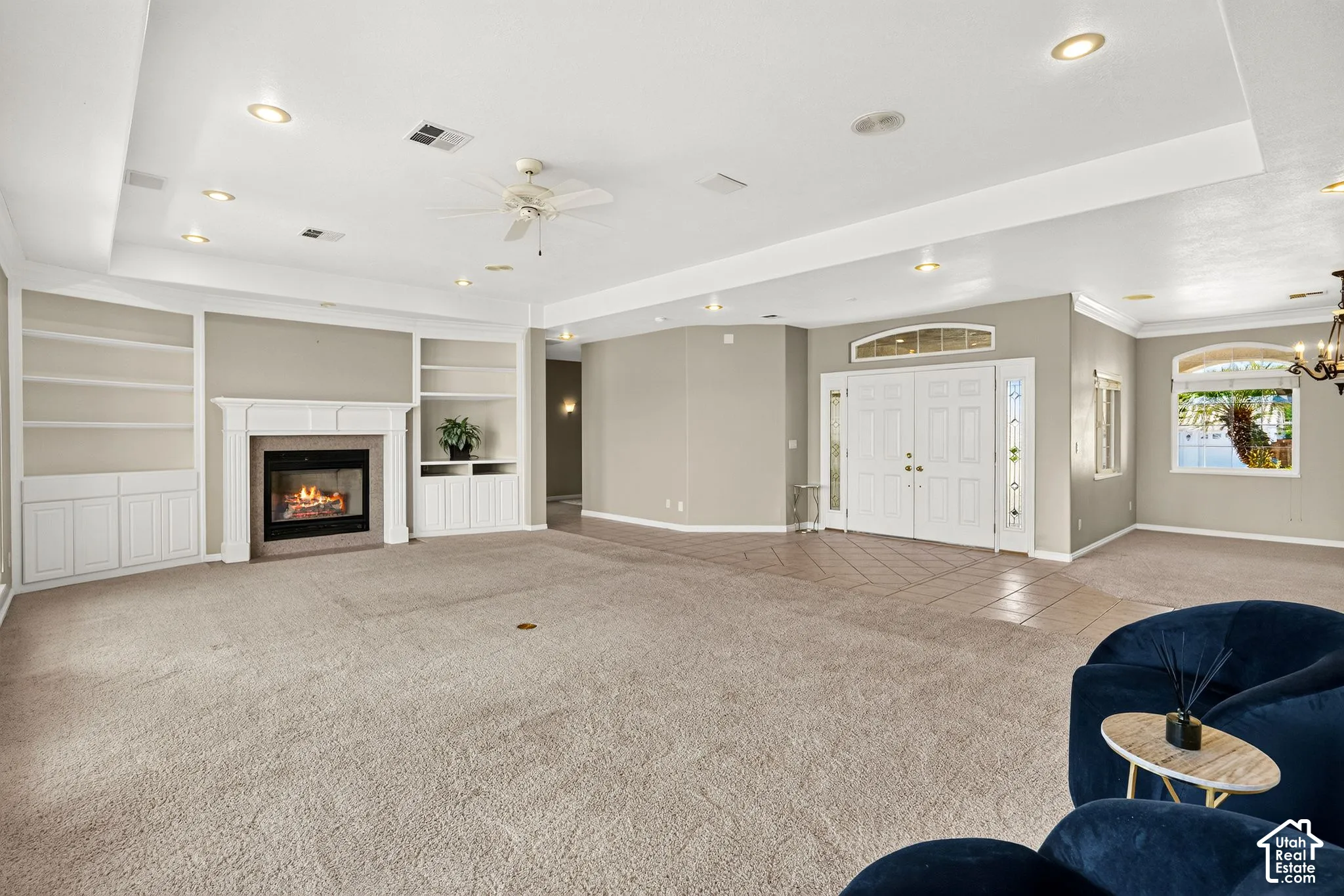 Built-in shelving and cabinetry framing a fireplace, recessed lighting, double entry doors with an arched transom, and arched windows