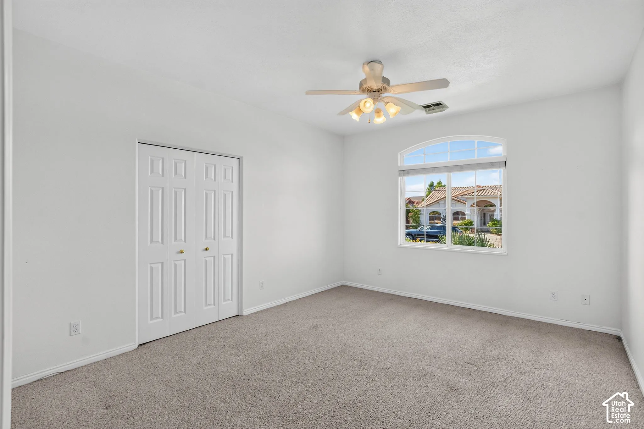Neutral wall paint, carpet flooring, a bifold closet, and an arched window