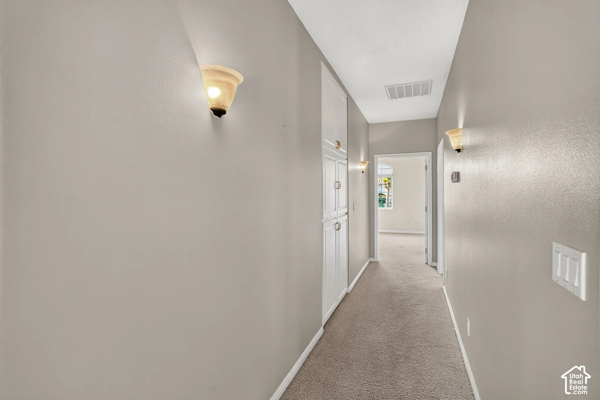 Bright hallway featuring neutral wall finishes, recessed ceiling lighting, carpet flooring, and multiple white interior doors with polished hardware
