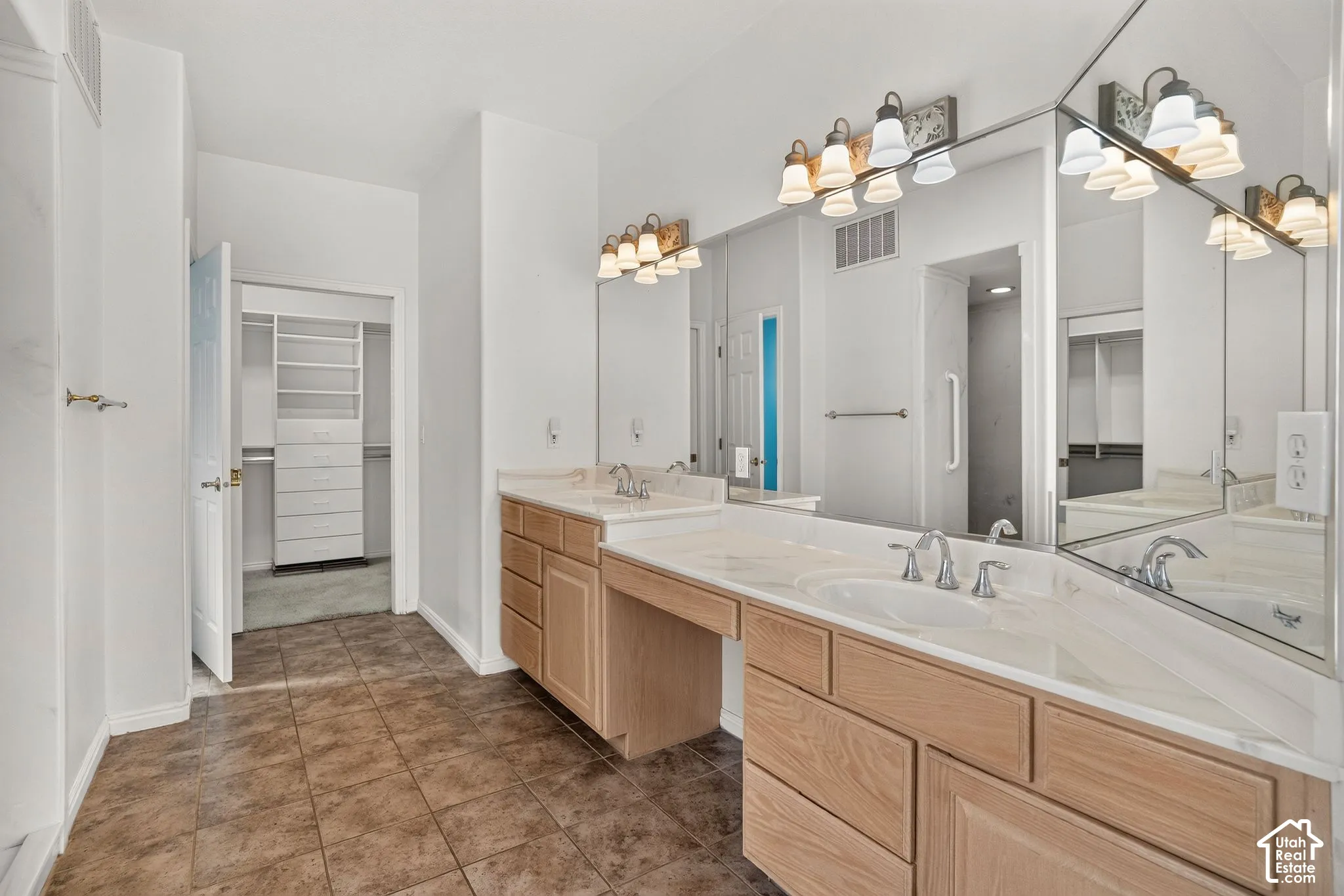 Dual vanity with integrated sinks, light wood-finish cabinetry, and expansive wall-mounted mirrors