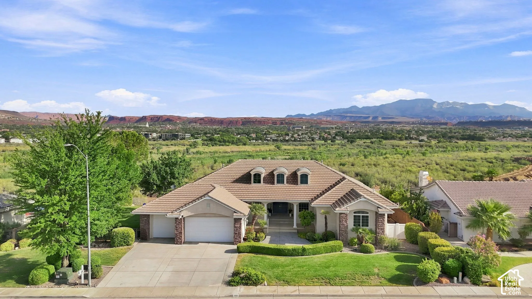 Stunning southwestern home showcasing a curved architectural roofline, arched entry portico, and dual-bay garage