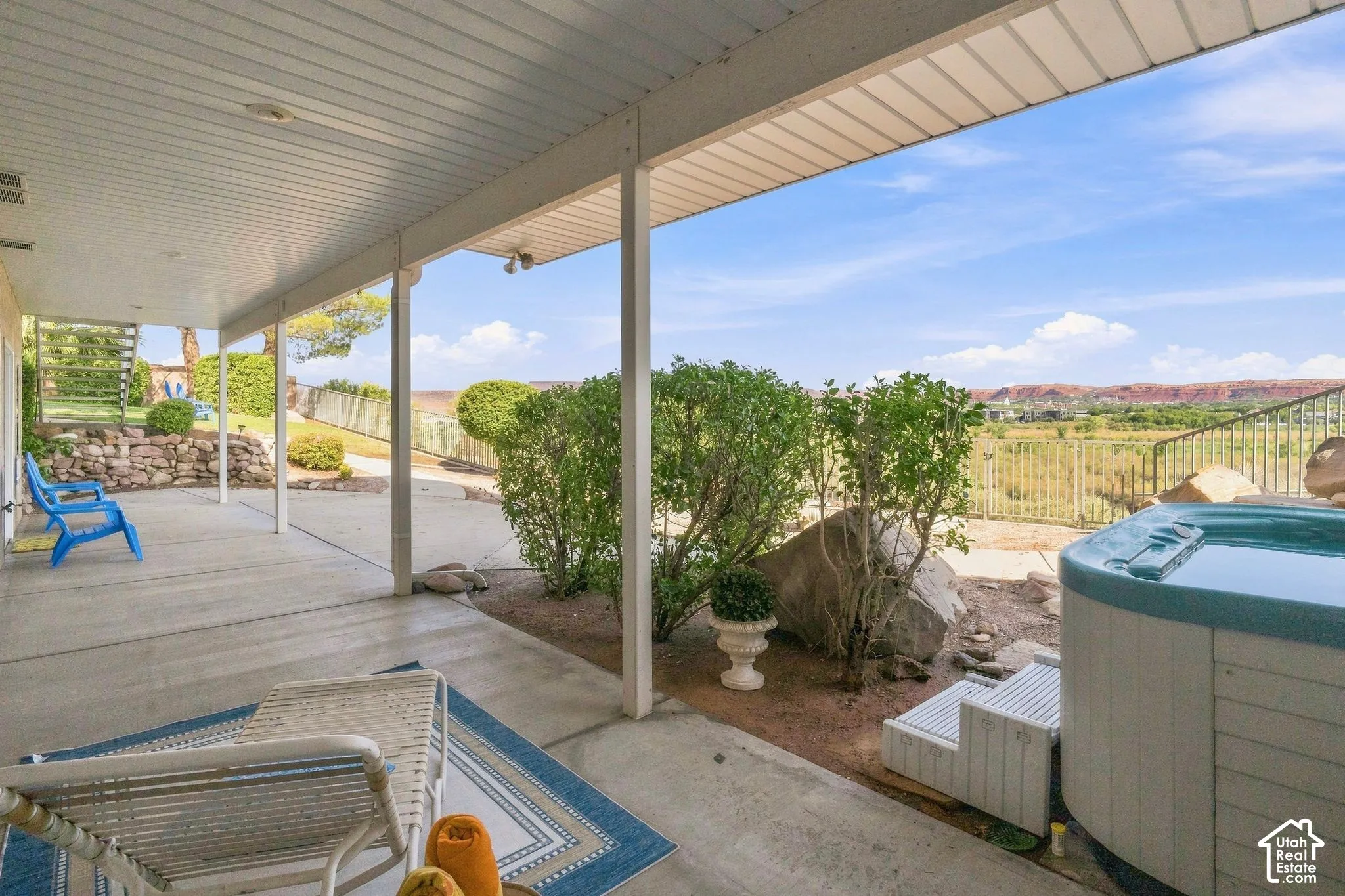 Spacious covered patio with concrete flooring, integrated hot tub, and open-air fencing