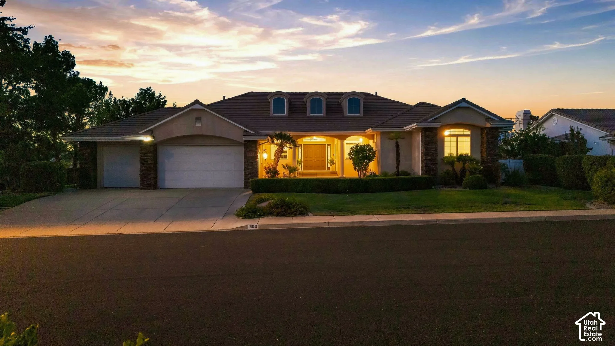 Single-story residence featuring a tile roof, stucco exterior with stone accents, and multiple garage doors