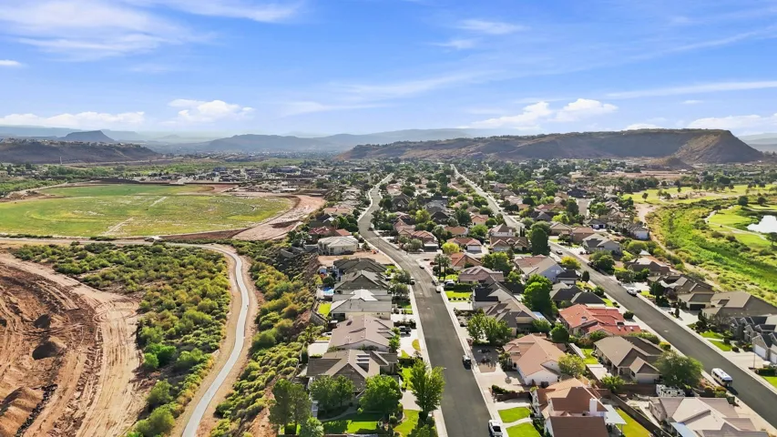 Residential street with detached homes, surrounded by natural desert landscaping and distant mountainous terrain
