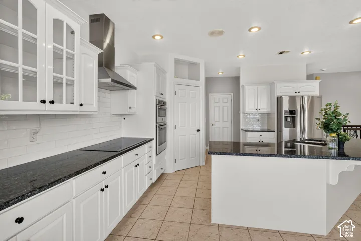 White cabinetry, dark countertops, tile flooring, stainless steel appliances, and recessed lighting