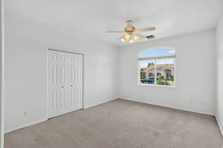 Neutral wall paint, carpet flooring, a bifold closet, and an arched window