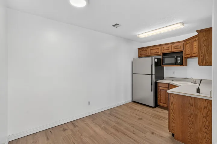 Wood-finish flooring, white walls, and a corner kitchen with wood cabinetry