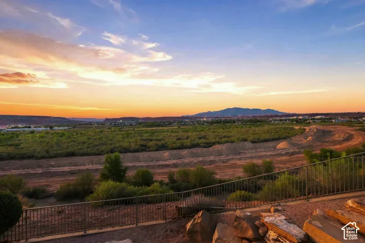 Expansive desert landscape with distant mountains, mature low-lying vegetation, and a metal perimeter fence