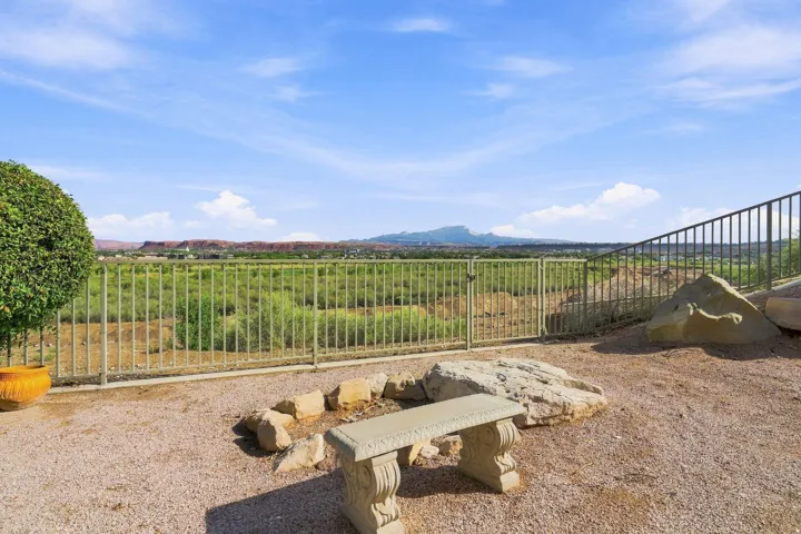 Gravel patio featuring a stone bench, fire pit area with natural rock surround, and metal fencing