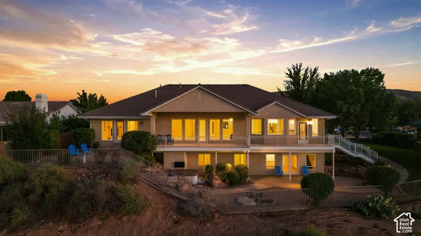 Two-story stucco exterior with multiple balconies, a lower-level patio, and a tiered landscaped property