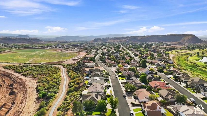 Residential street with detached homes, surrounded by natural desert landscaping and distant mountainous terrain