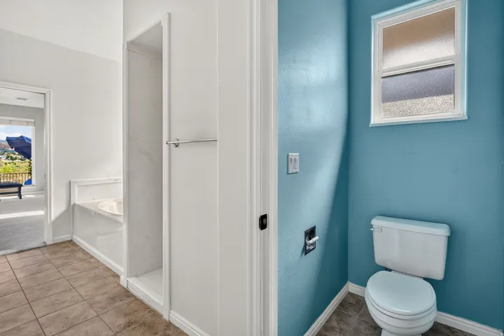 Spa-inspired bathroom featuring vibrant teal accent walls, a white ceramic toilet with elongated bowl, pedestal sink with chrome fixtures, and a frameless glass-enclosed shower enclosure with white subway tile surround