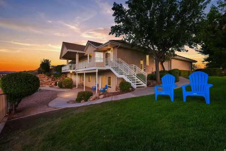 Multi-level exterior with balconies, featuring a concrete patio, landscaped rock gardens, and a sloped lawn