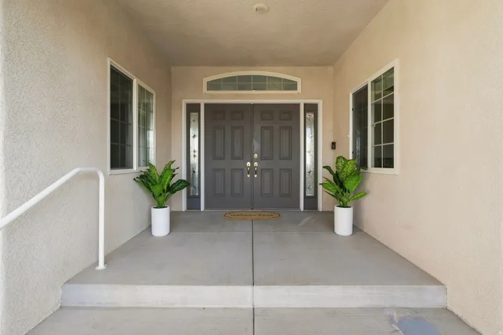 Double entry doors with decorative glass panels, transom window, and dual side windows