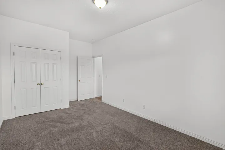 Spacious bedroom with neutral wall finishes, plush carpeting, and dual closets featuring white six-panel doors