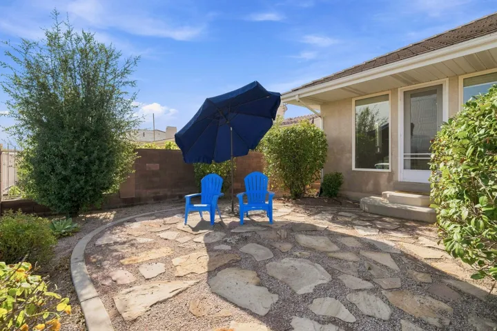 Expansive backyard retreat featuring a flagstone patio with curved border detailing, mature landscaping with established shrubs and climbing vines, and a freestanding patio umbrella for shade
