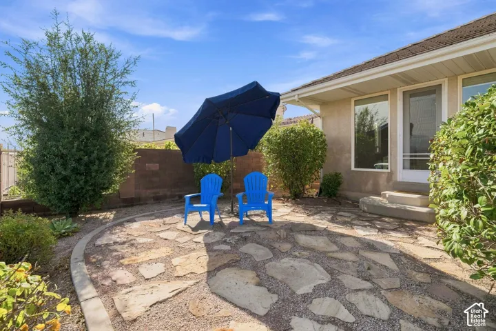 Expansive backyard retreat featuring a flagstone patio with curved border detailing, mature landscaping with established shrubs and climbing vines, and a freestanding patio umbrella for shade