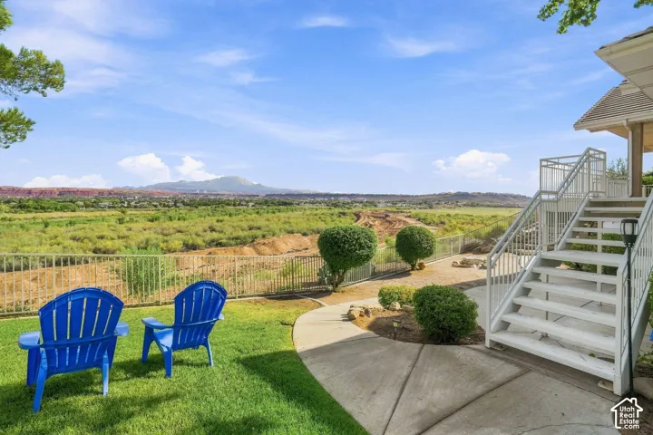 Expansive grounds with manicured lawn and mature landscaping, featuring a concrete patio, metal-railing deck with exterior staircase, and Adirondack seating