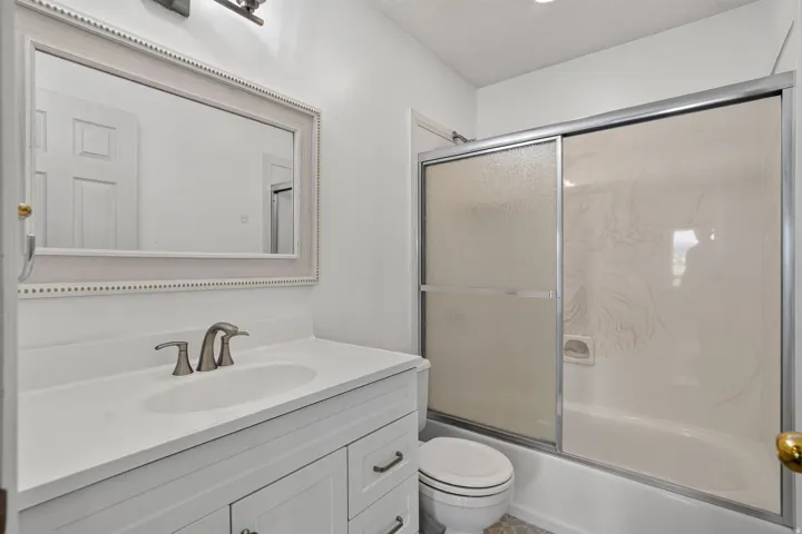 White vanity with brushed nickel hardware, integrated sink, and brushed nickel faucet