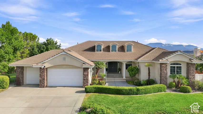 Mediterranean-style exterior with a tile roof, stucco finish, stone accents, and multiple garage doors