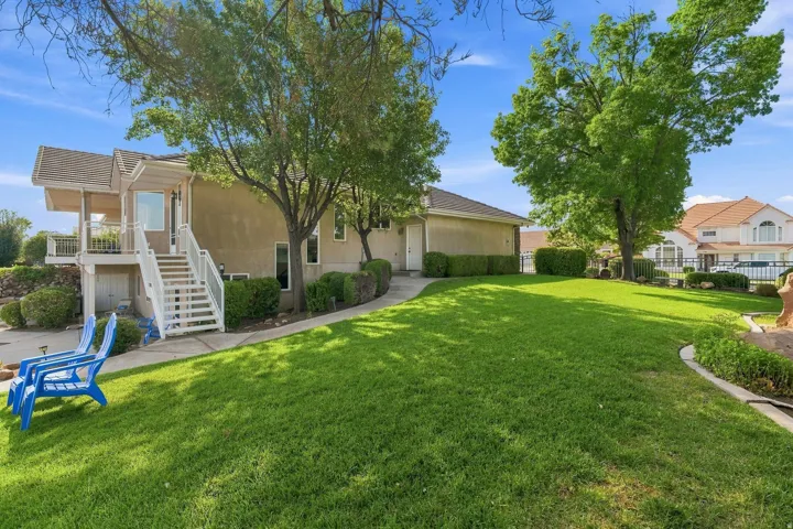 Expansive backyard featuring a manicured lawn, mature shade trees, and curved landscape borders