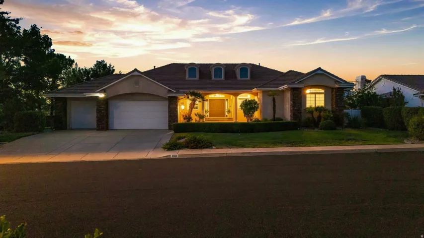 Single-story residence featuring a tile roof, stucco exterior with stone accents, and multiple garage doors