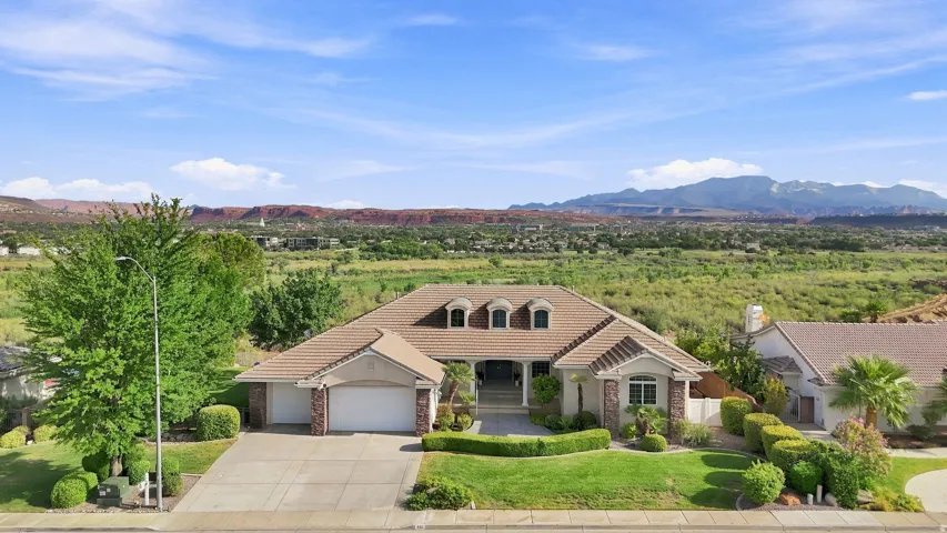 Stunning southwestern home showcasing a curved architectural roofline, arched entry portico, and dual-bay garage